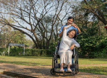 Asian nurse or physiotherapist caring for elderly woman sitting wheelchair. Asian female nurse takes