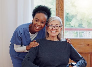 Senior care, caregiver and old woman with wheelchair, portrait and smile in health at nursing home.